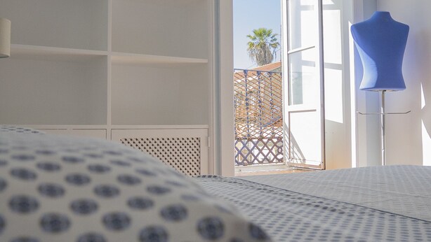 Une chambre à coucher comprenant un lit, une armoire et une fenêtre donnant sur un balcon.