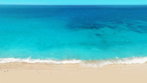 Una playa con agua turquesa cristalina y una orilla arenosa.