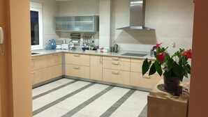 Una cocina moderna con una isla grande, electrodomésticos de acero inoxidable y una campana extractora.