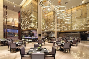 A spacious hotel lobby with multiple dining areas, modern chandeliers, and a large bar area. - Wanda Realm Guangyuan (Guangyuan)