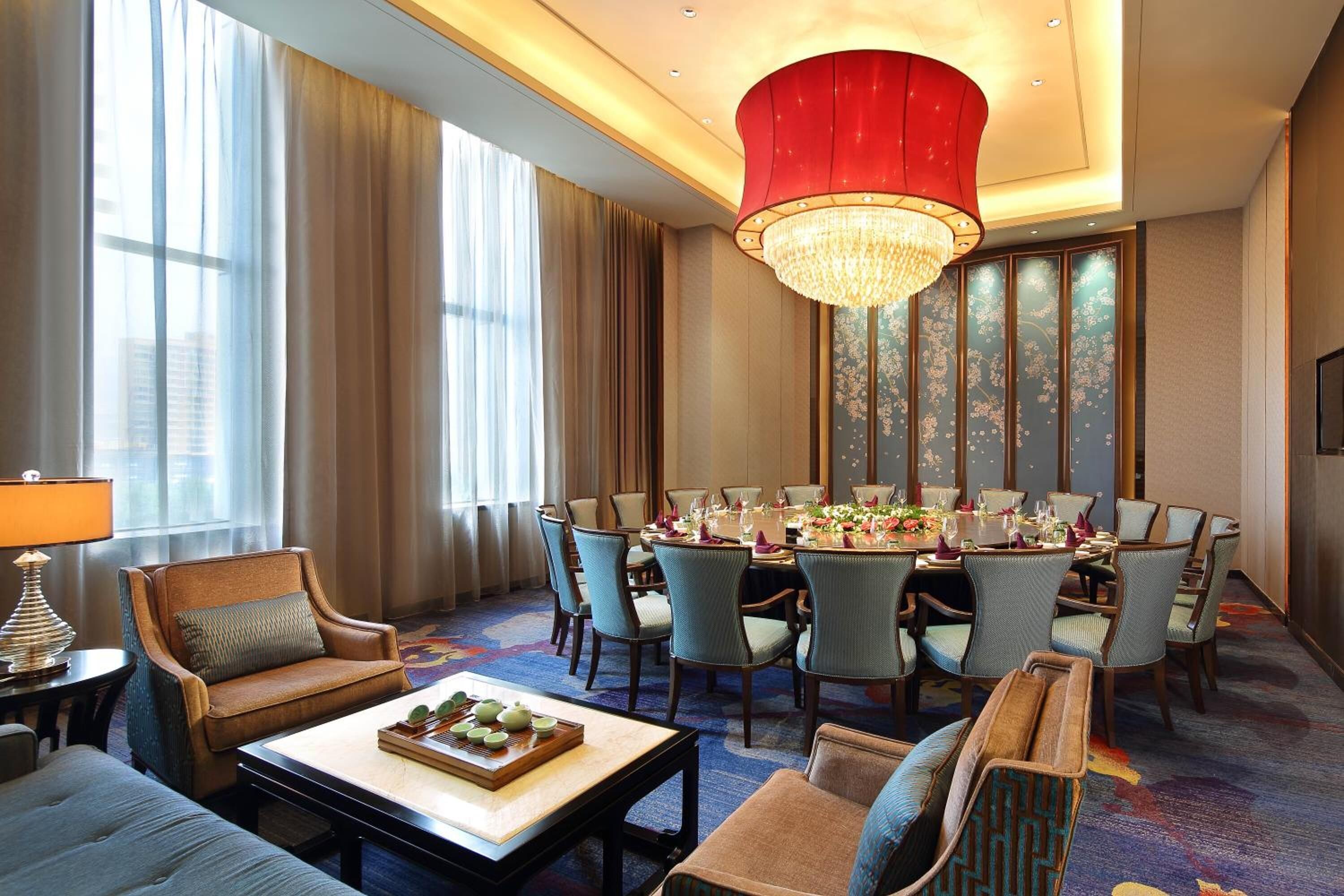 A hotel room with a dining area, a sofa, a coffee table, and a chandelier.