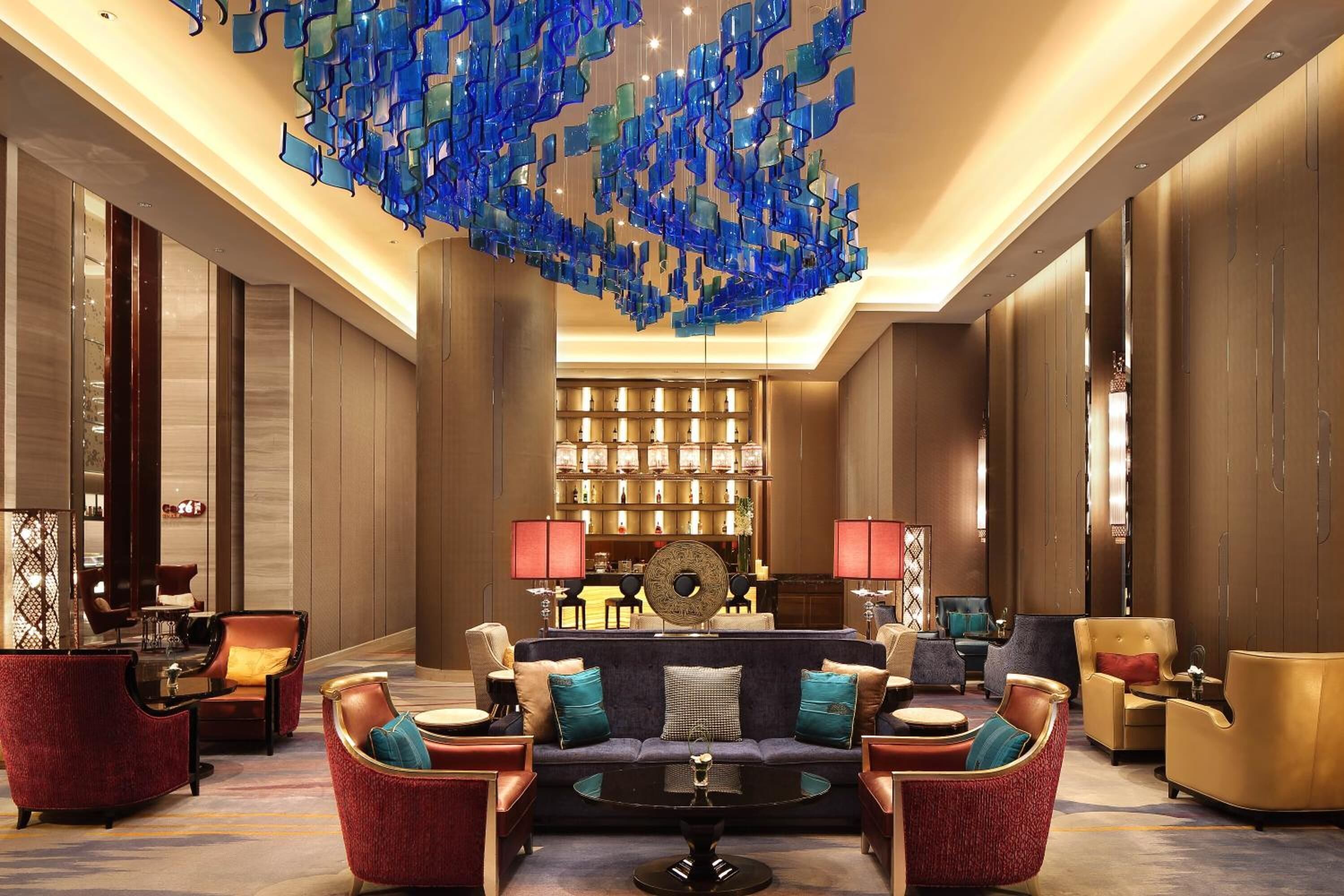 A spacious lobby with a central seating area, a decorative ceiling installation, and a well-lit background with a patterned wall.