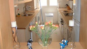 Et køkken med moderne hårde hvidevarer, en vask og en vase med blomster på bordpladen.