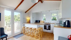 A kitchen with wooden stools, a microwave, and a coffee machine.