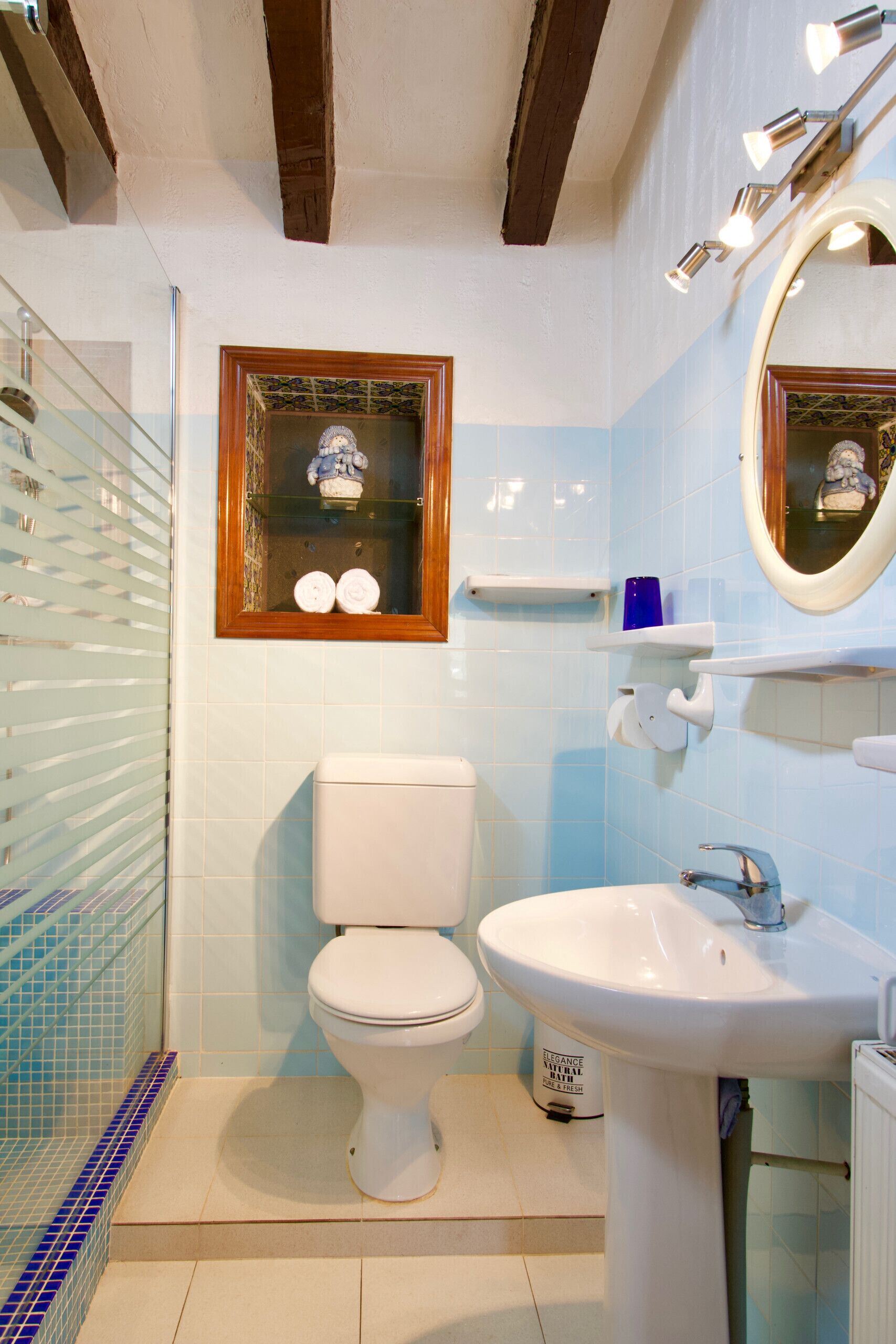 A bathroom with a toilet, sink, and a window with decorative items.