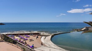 Ein Küstenresort mit Poolbereich, Liegestühlen am Strand und Blick auf den Ozean.