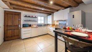 Una cucina moderna con travi in legno, pensili bianchi e un'area pranzo con tavolo apparecchiato per due.