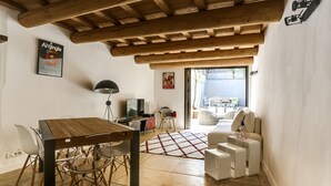 Un soggiorno moderno con un tavolo da pranzo in legno, sedie bianche, un televisore e un divano.