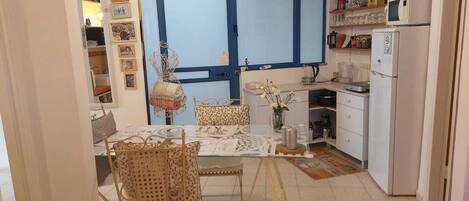 A compact kitchen with a dining area, featuring a white refrigerator, a microwave, and a sink.
