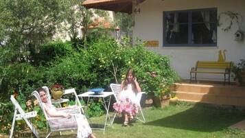 Set amidst lush gardens, this charming house features a patio area with a table and chairs.