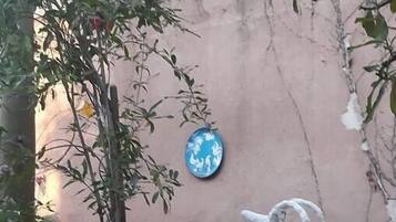 A garden with a white bird sculpture, a blue decorative plate, and various plants.