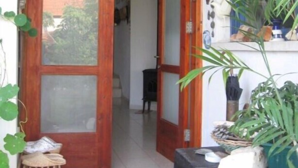 Una puerta de madera con paneles de vidrio, un taburete de madera pequeño y una planta en maceta.