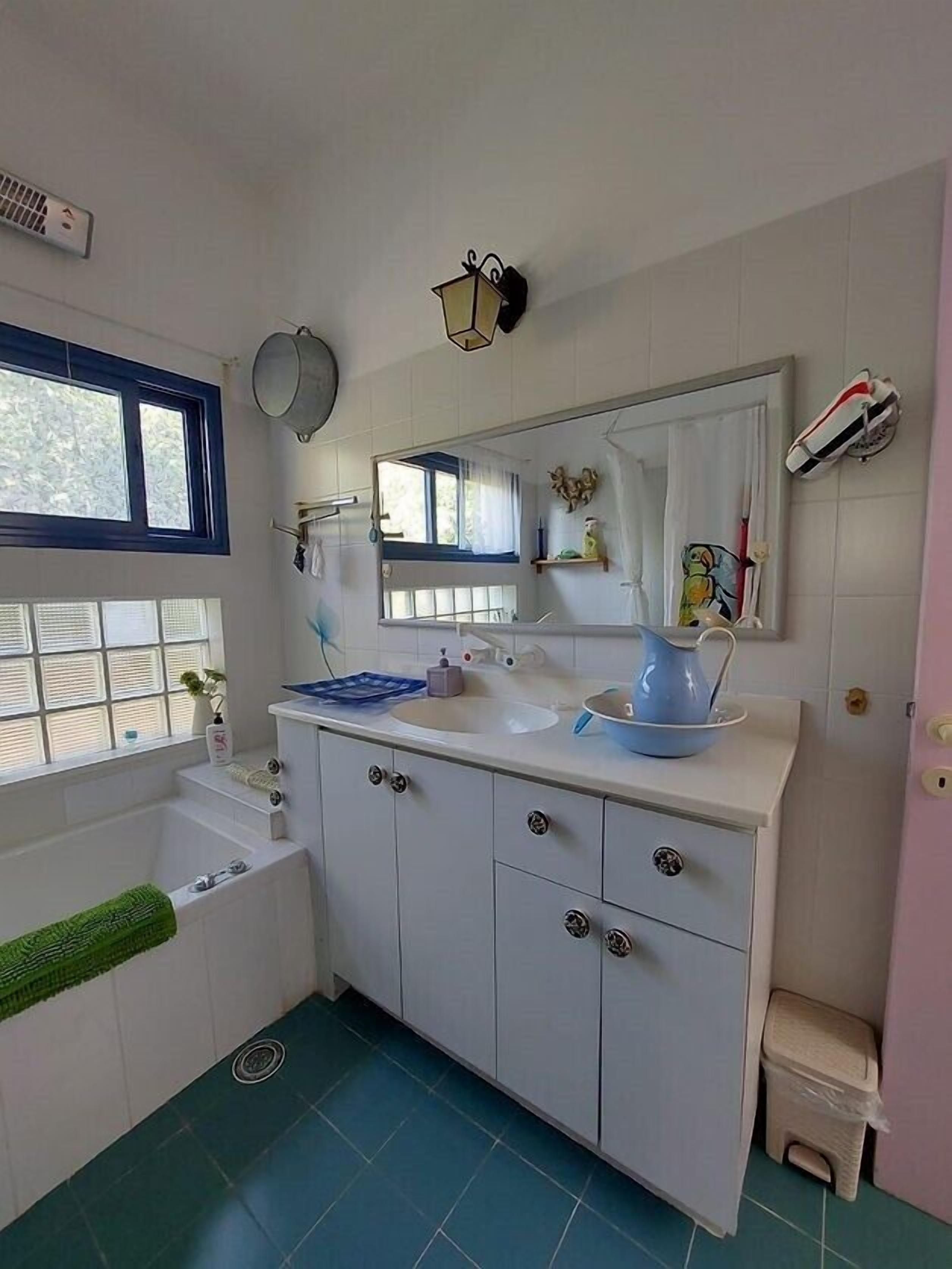 Une salle de bain avec un meuble-lavabo blanc, une baignoire, une fenêtre et un miroir.