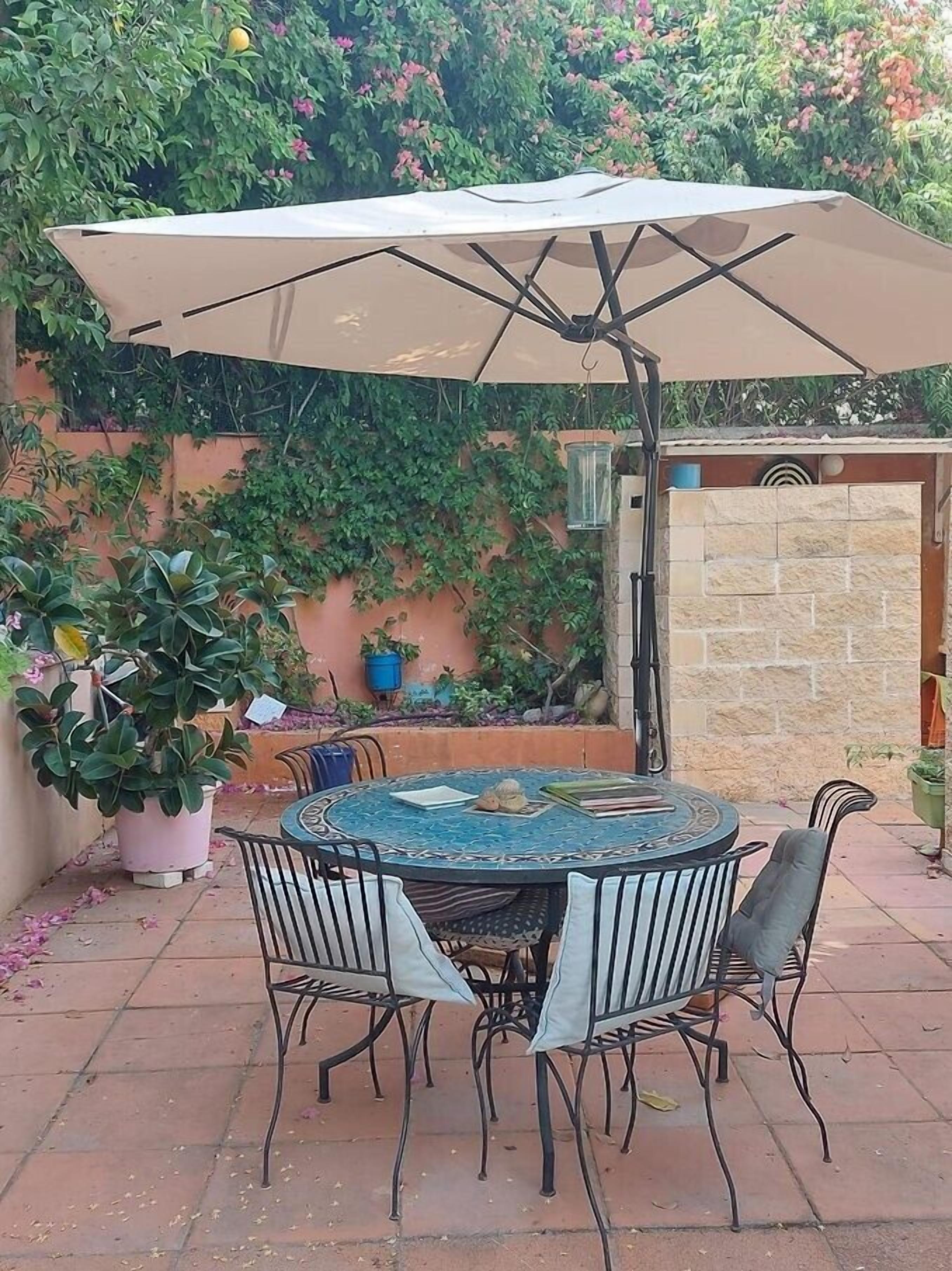 A patio with a round table, four chairs, and a large umbrella.