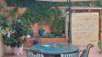 A patio with a round table, four chairs, and a large umbrella.