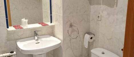 A bathroom with a white sink, a mirror, a toilet, and a towel rack.