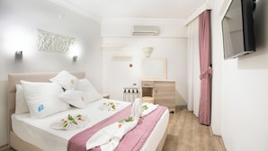 A hotel room with a bed, bedside table, mirror, and a TV mounted on the wall. - Sea Bird Hotel (Didim)
