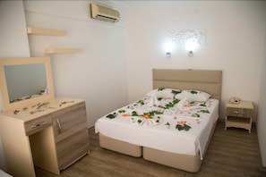 A bedroom with a bed, bedside table, dresser, and a mirror. - Sea Bird Hotel (Didim)