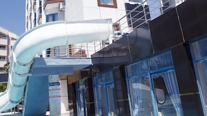 A modern hotel with a pool area, including a water slide and a clear view of the building's exterior. - Sea Bird Hotel (Didim)