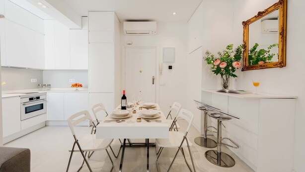 A modern kitchen with white cabinetry, a dining table set for four, and a bar area with stools. - The Viso Smart III (NEW) (Madrid)