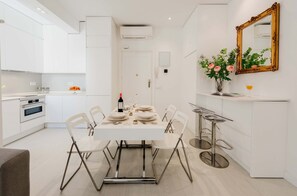 A modern kitchen with white cabinetry, a dining table set for four, and a bar area with stools. - The Viso Smart III (NEW) (Madrid)
