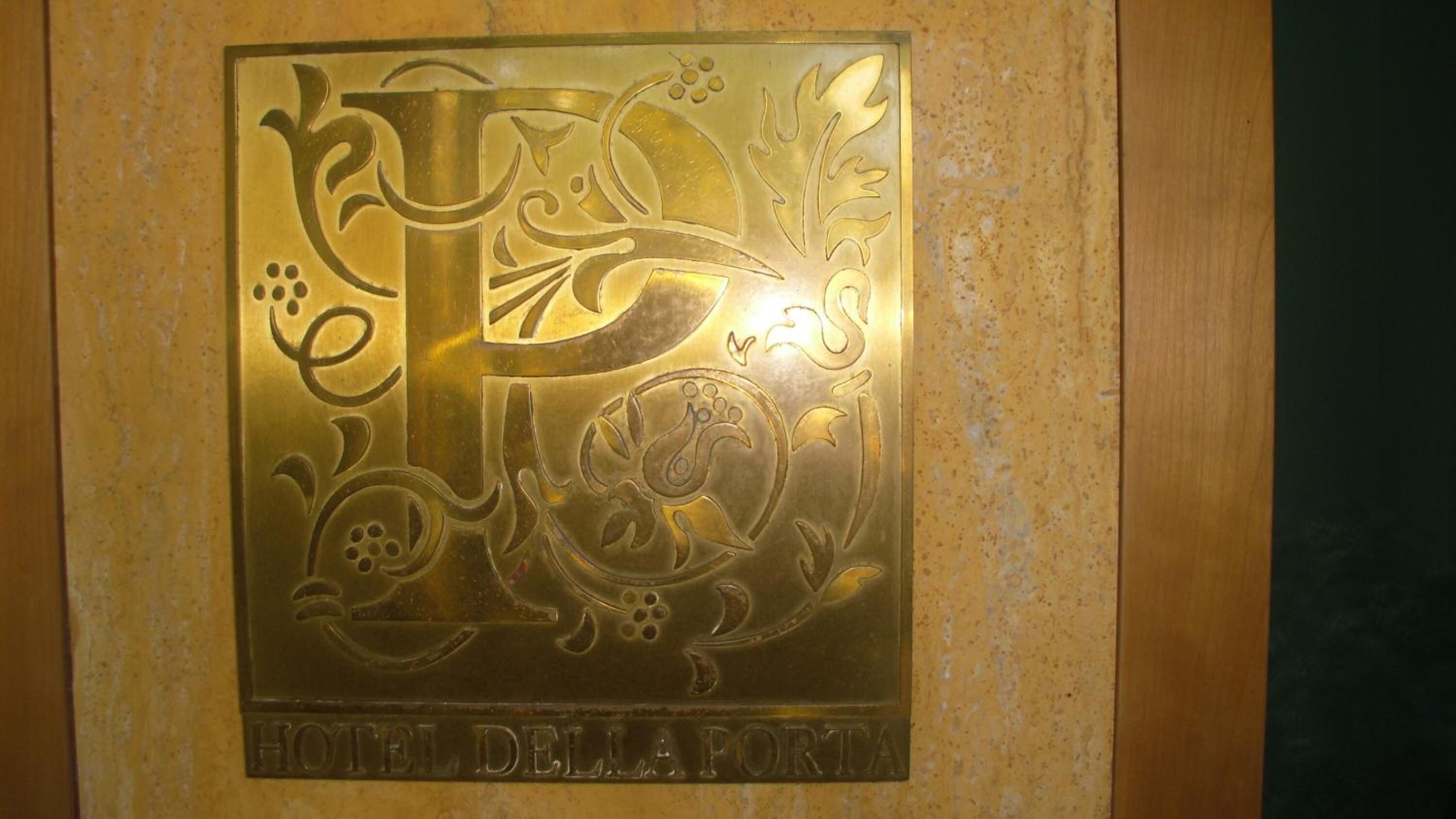 A plaque with a decorative emblem and the text "HOTEL DELLA PORTA".