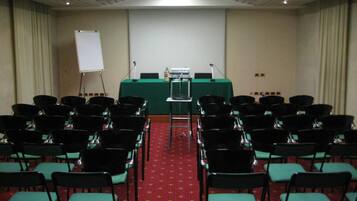 Un salón de conferencias con filas de sillas, un atril y una pizarra.