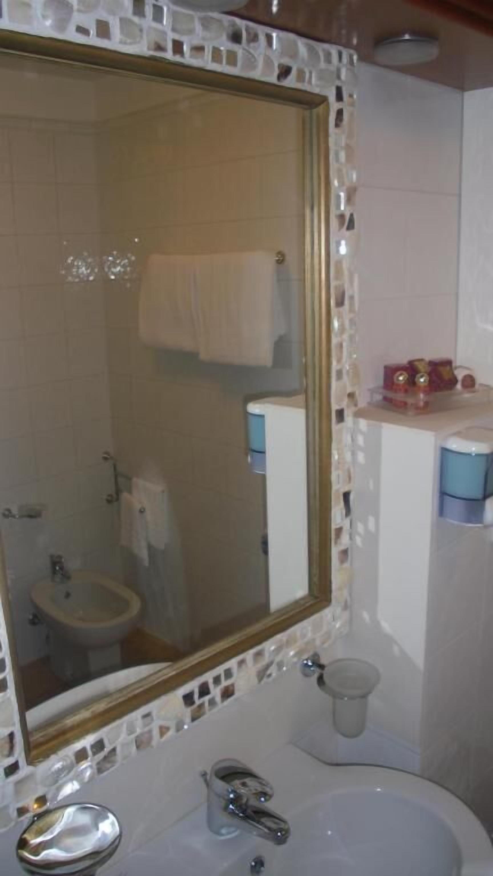 A bathroom with a large mirror, a sink, a bidet, and a towel rack.