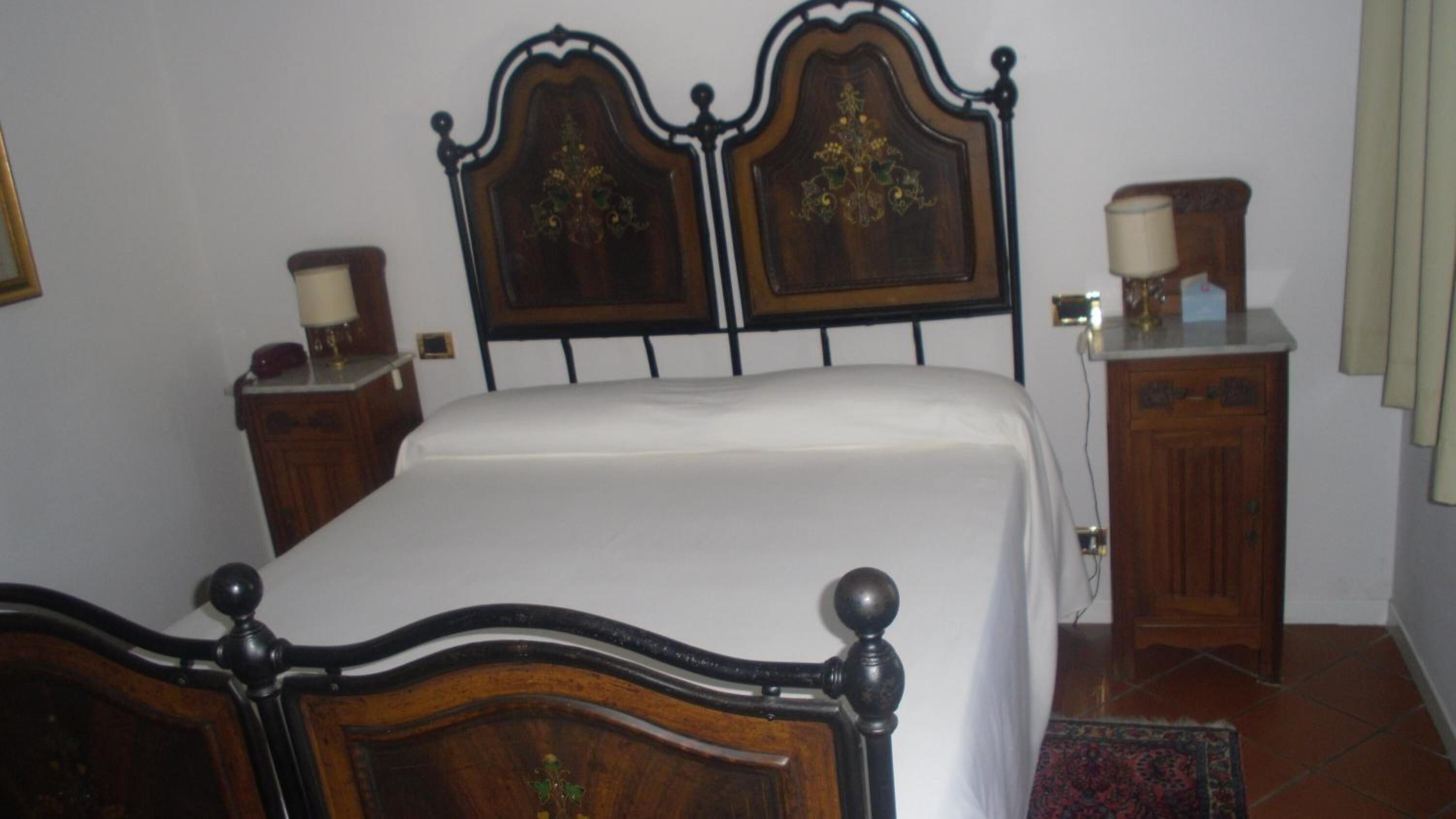 A bedroom with a wooden bed, a nightstand, a dresser, and a lamp.