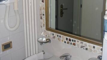 Um banheiro com pia branca, espelho com moldura em mosaico e vaso sanitário.