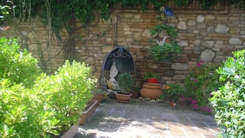 A stone wall with a statue, potted plants, and a small garden area.