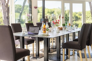 A modern dining area with a long table, chairs, and a laptop. - Hotel Les Rocailles (Montagnac)