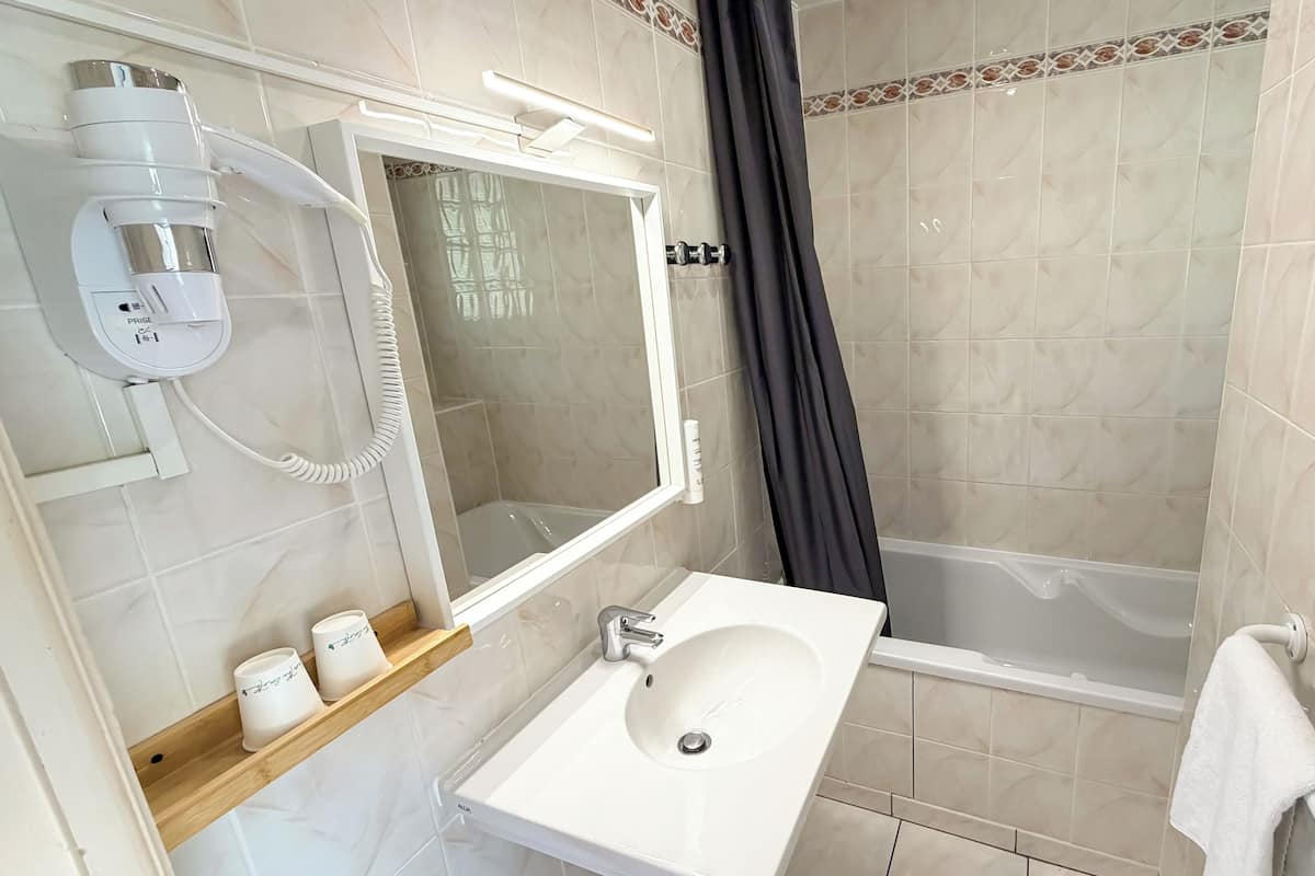 A bathroom with a white sink, mirror, and shower curtain.