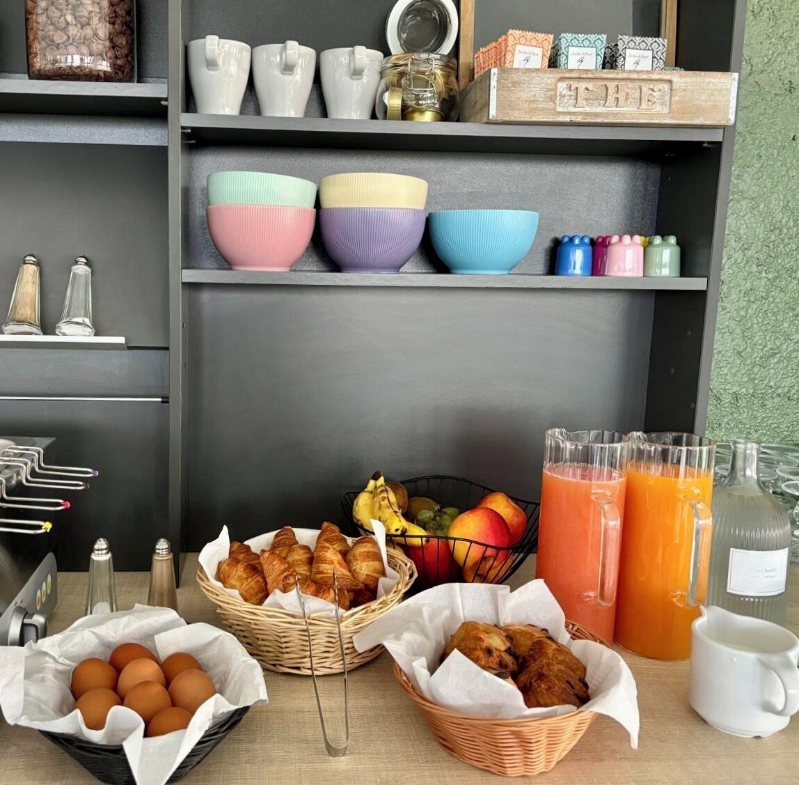 A breakfast setup with croissants, eggs, fruit, and orange juice.