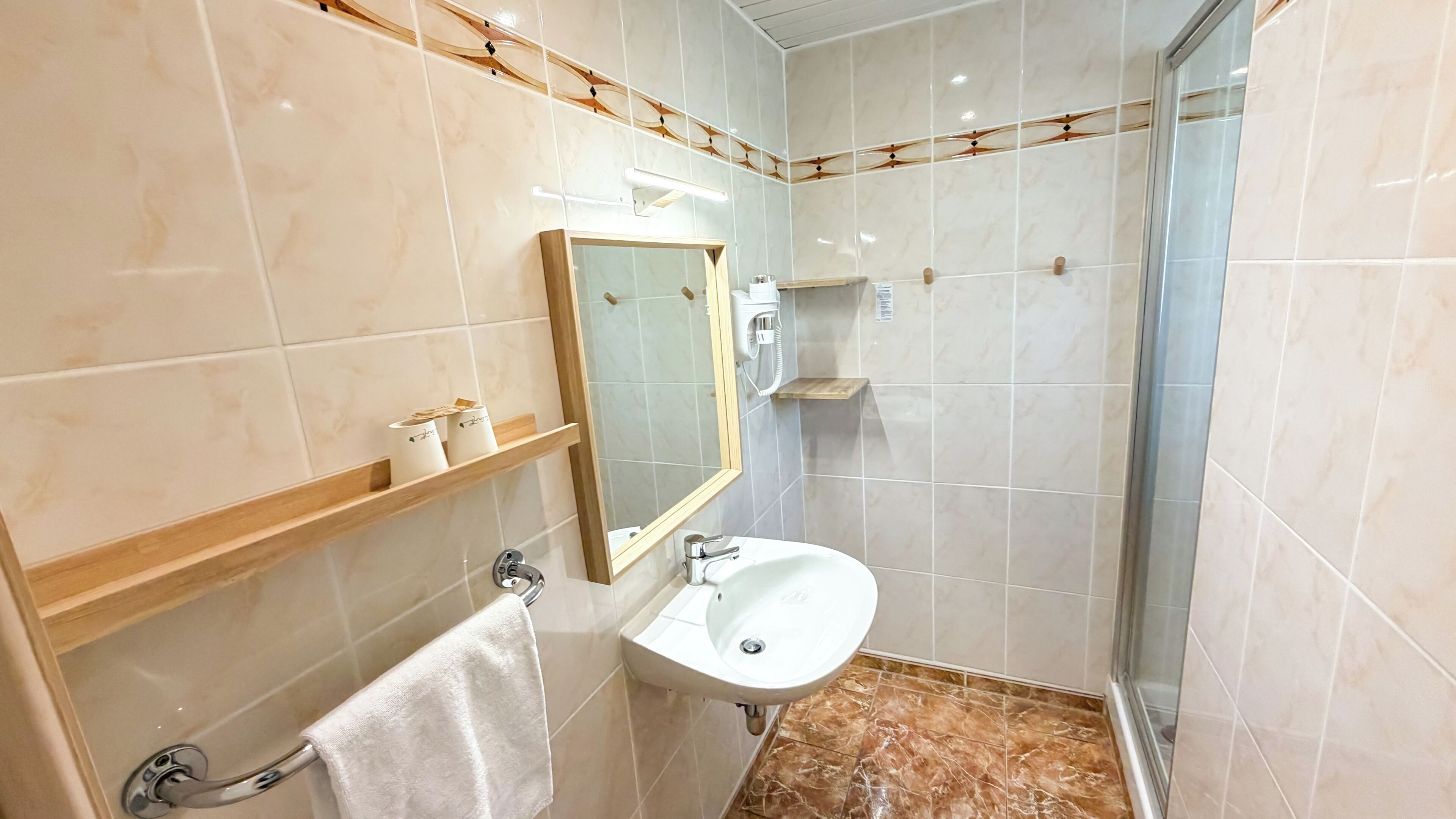A bathroom with a white sink, a mirror, a towel rack, and a shower area.
