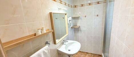 A bathroom with a white sink, a mirror, a towel rack, and a shower area.