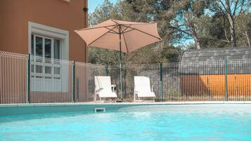 Een seizoensgebonden buitenzwembad, parasols voor strand/zwembad