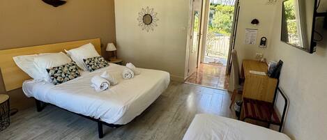 A hotel room with two beds, a desk, a chair, a lamp, and a door leading outside.