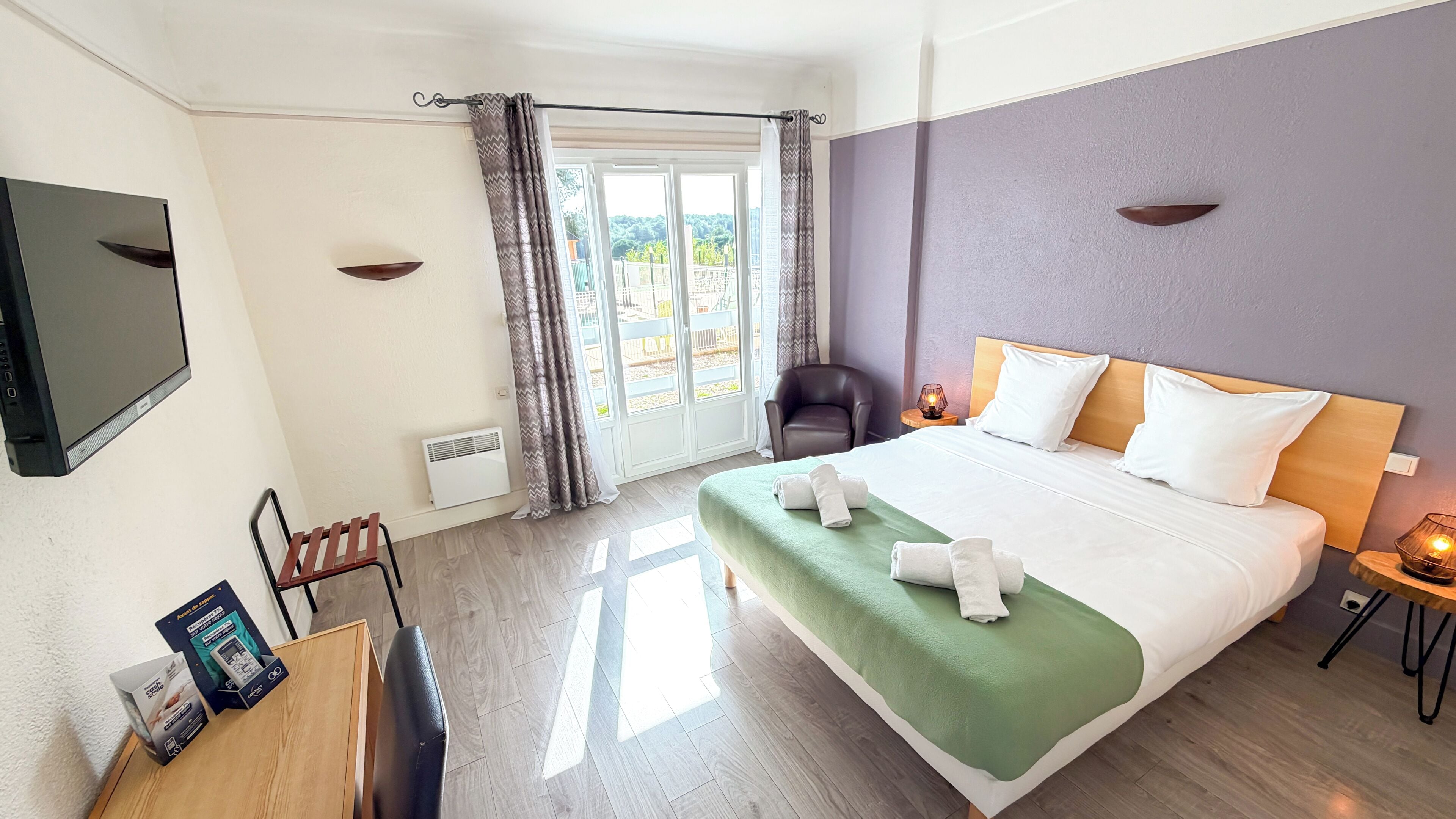 Une chambre d’hôtel avec un lit, une chaise, un bureau, une télévision et une vue sur l’extérieur.
