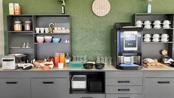 A breakfast bar with a coffee machine, various food items, and storage cabinets.