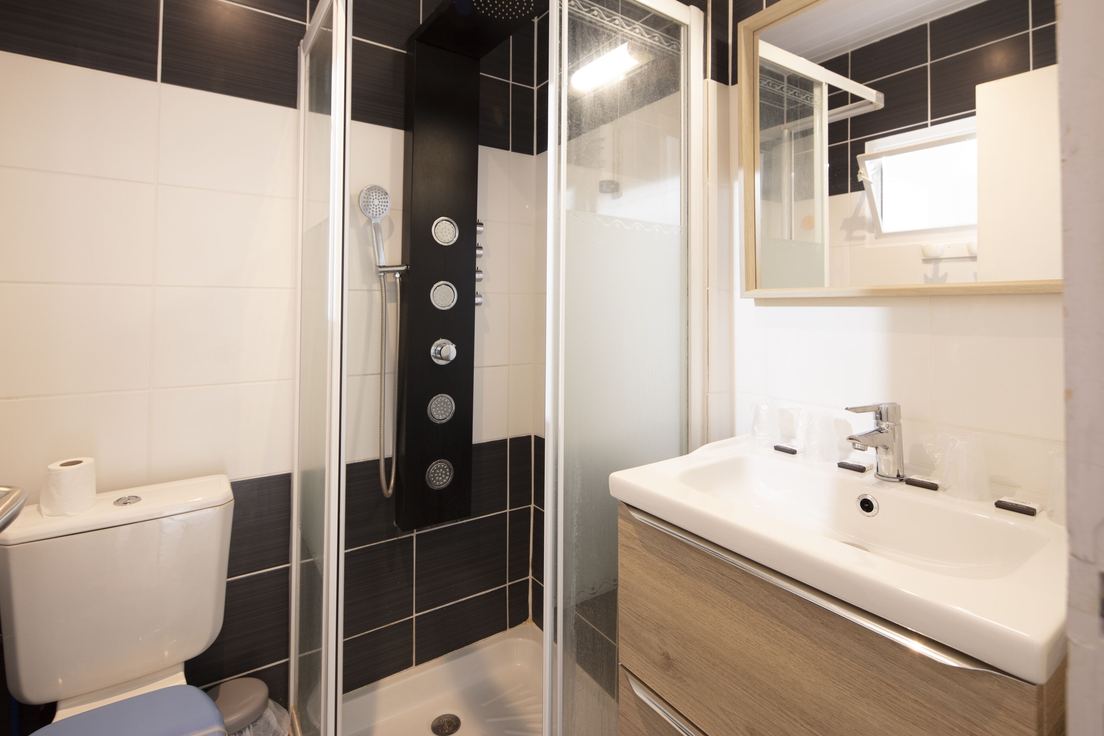 Een moderne badkamer met een douchecabine van glas, een witte wastafel en een spiegel erboven.