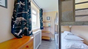 A bunk bed room with a window, a radiator, a desk, and a curtain with dinosaur prints. - D61 Kiamena, Riviere Towans (Hayle)