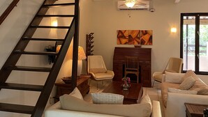 A spacious living area with a staircase, a fireplace, and a large window. - Charming Aruban house (Noord)
