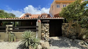 A building with a stone facade, a tiled roof, and a cactus in the foreground. - Charming Aruban house (Noord)