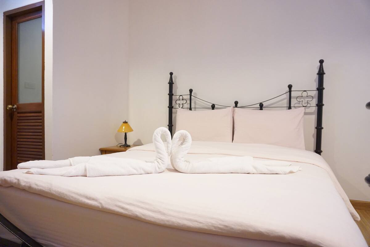 A neatly made bed with a simple headboard and a small bedside table with a lamp.