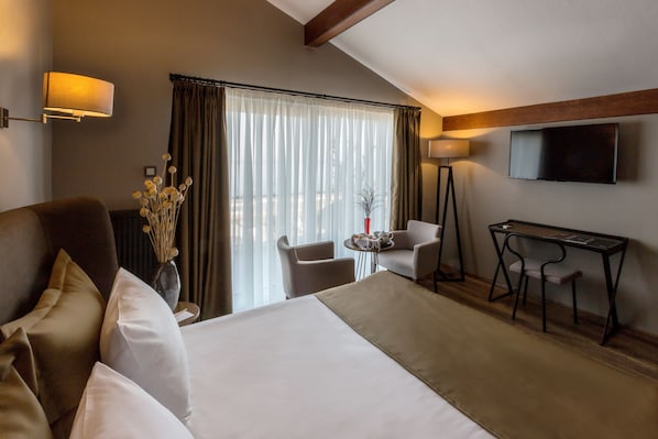 A hotel room with a large bed, a desk, two chairs, a TV, and a window with curtains. - Marin Otel & Restaurant (Atakum)