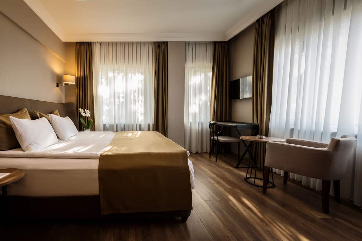 Camera d'albergo con un letto grande, una scrivania, una sedia e una televisione.