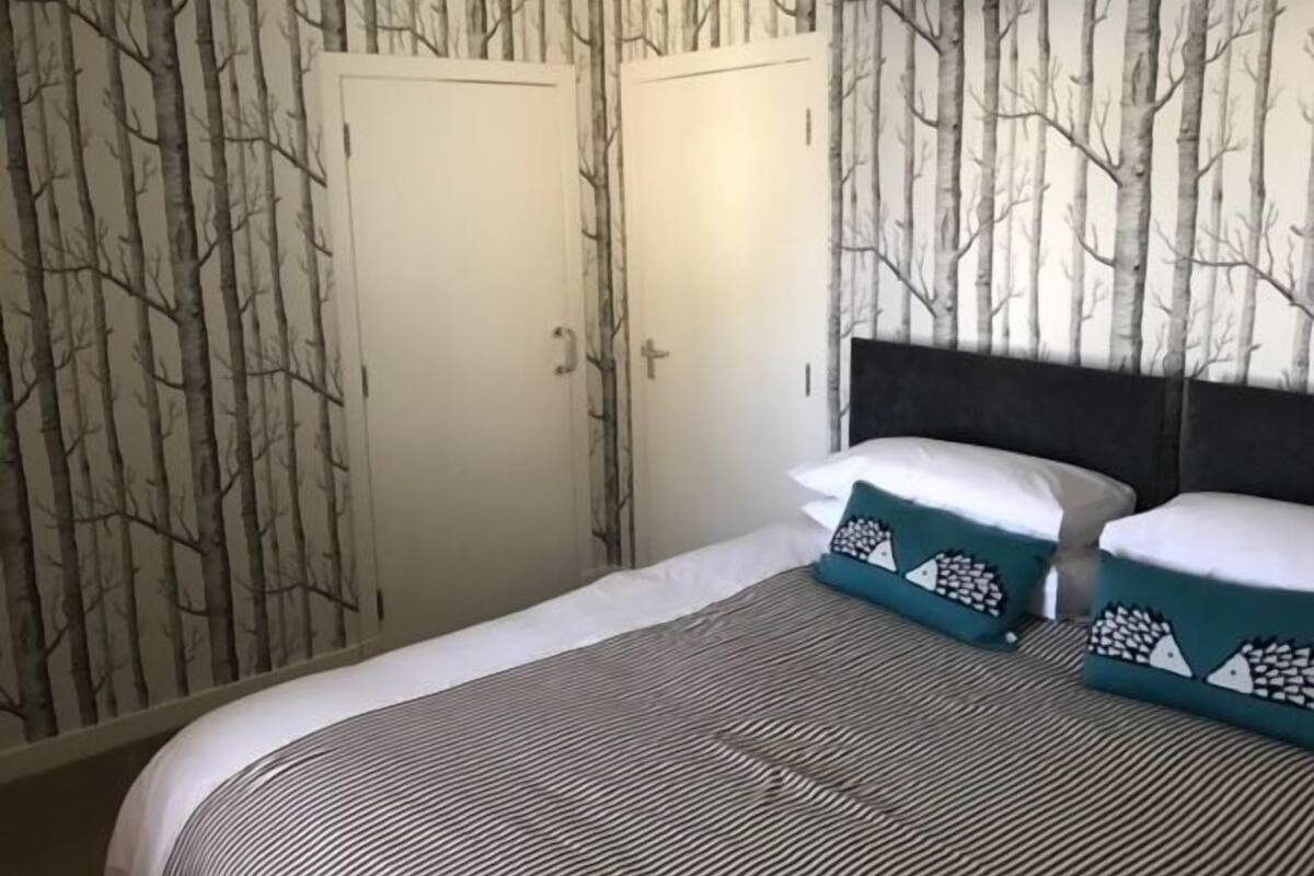 Ein Schlafzimmer mit einem Bett, zwei Türen und einer Wand mit Baummuster.