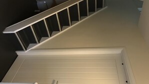 A staircase with a white handrail and a white door at the bottom. - Geise Farm Services (Thurso)