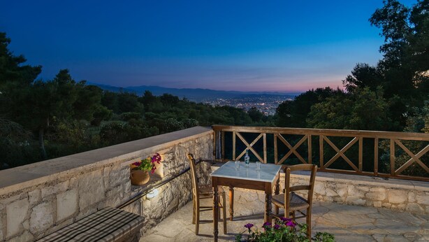 A terrace with a table and chairs, overlooking a cityscape at dusk. - Koukounari luxury villa with pool. A timeless paradise!  (Chania)